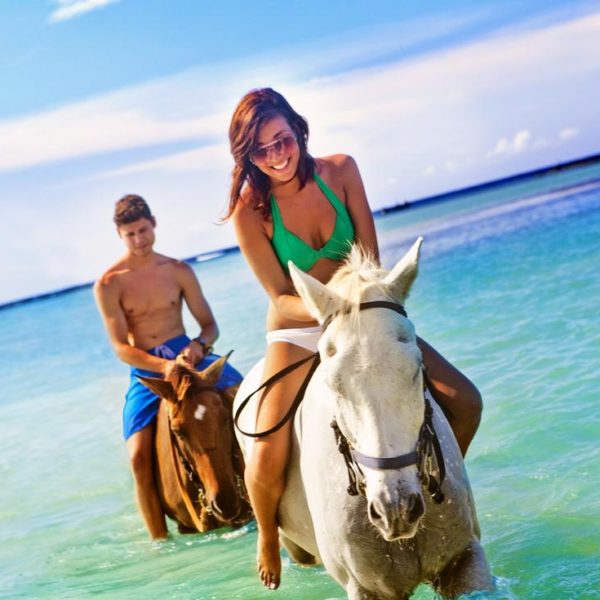Couple Horseback riding ocean honeymoon