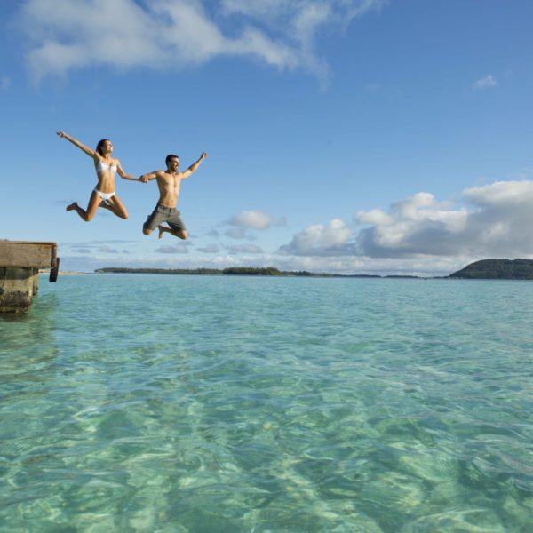 Tahiti Bora Bora Romantic Vacation Couple Jumping into Ocean Pier